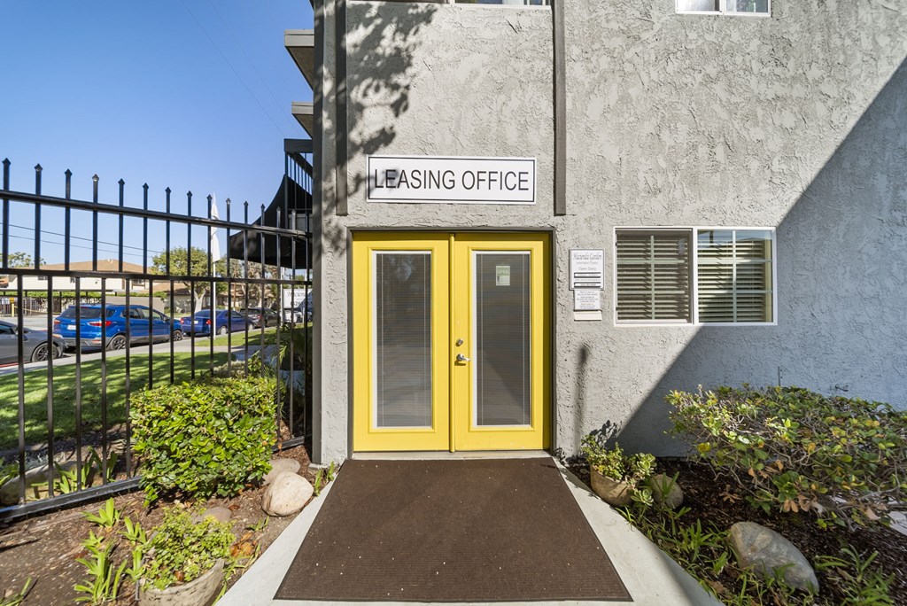 A building with a yellow door and a sign that says "Leasing Office".
