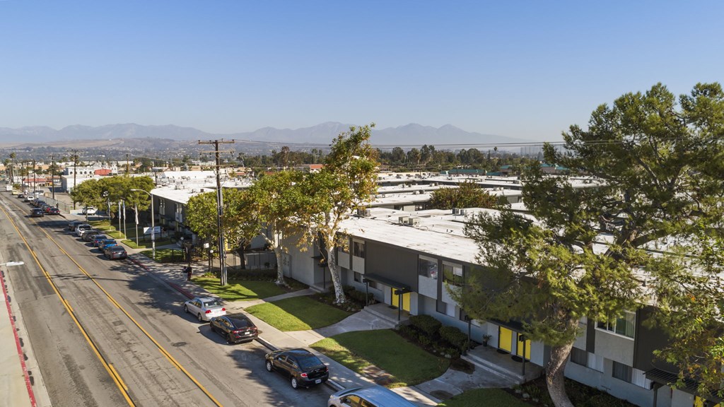 A street view of a residential area with cars parked on the side of the road.