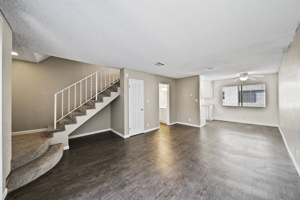 A spacious room with a staircase and wooden flooring.