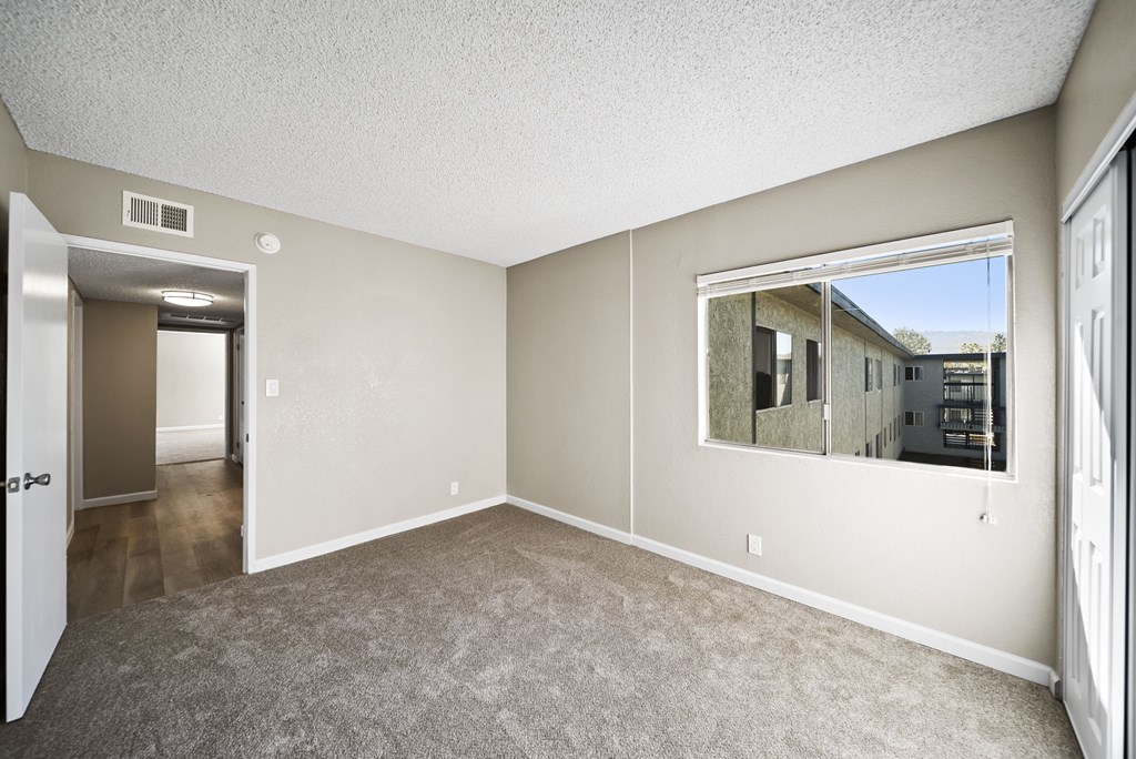 A room with a carpeted floor and a large window.