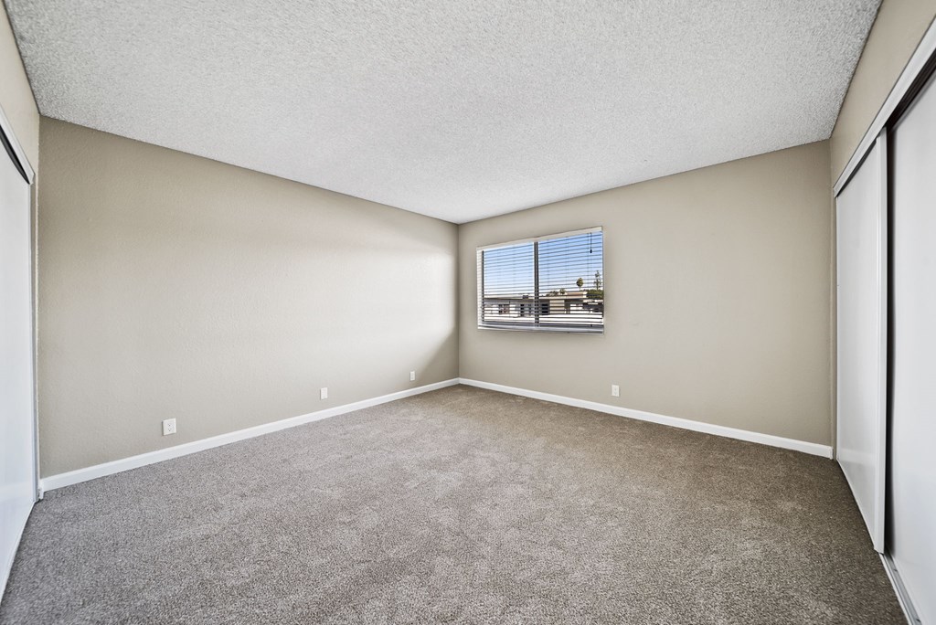 Empty room with carpeted floor and a window.