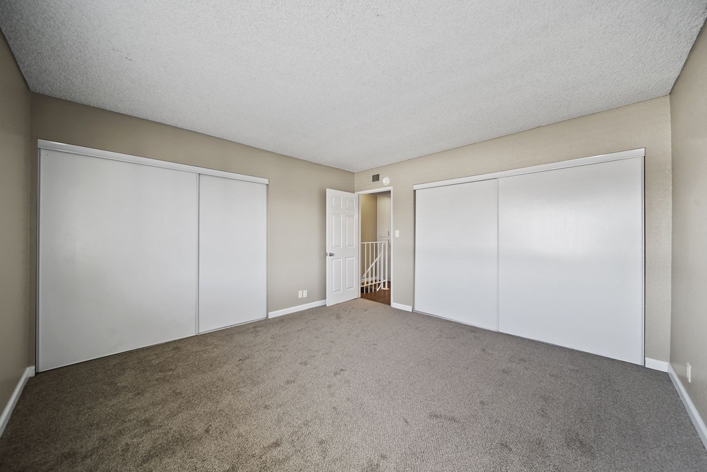 A room with white closet doors and carpeted floor.