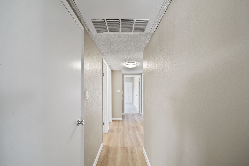 A long hallway with doors on either side and a light on the wall.