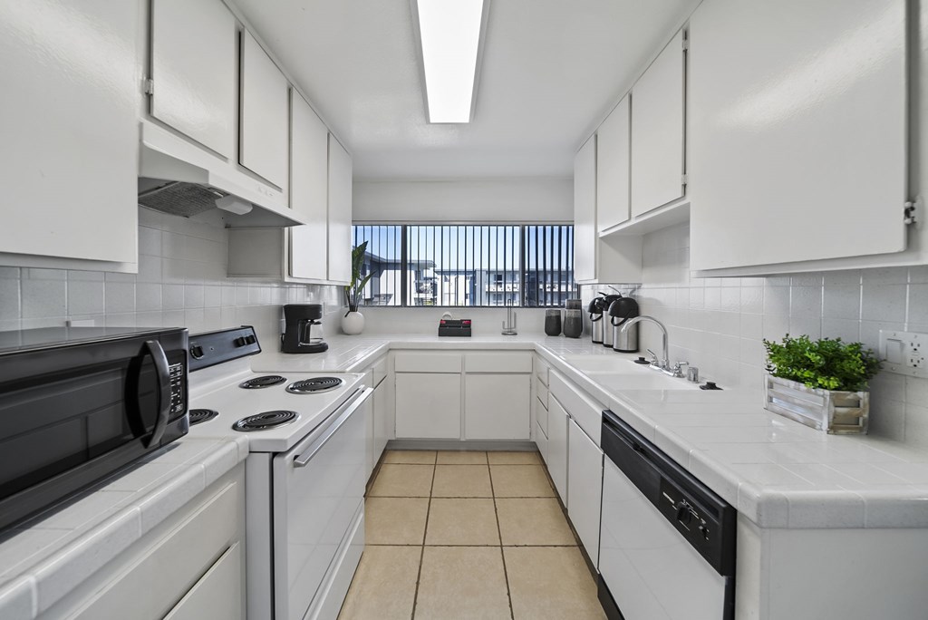 A kitchen with white cabinets and appliances.