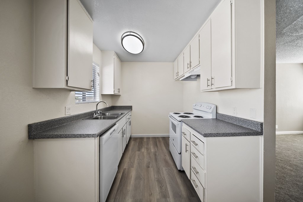 A kitchen with white cabinets and a black counter top.