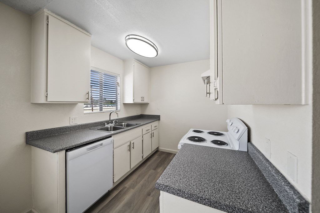A kitchen with white cabinets and a black countertop.