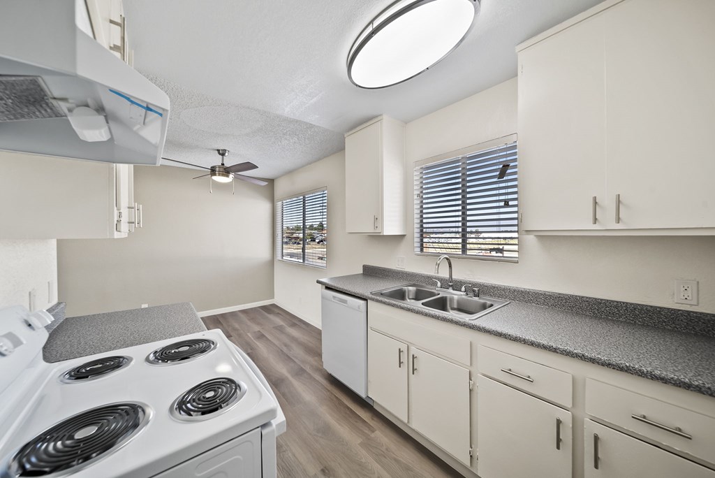 A kitchen with a white stove top oven and white cabinets.