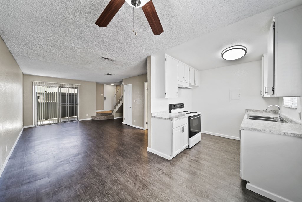 A spacious kitchen with a fan on the ceiling and a stove top oven.
