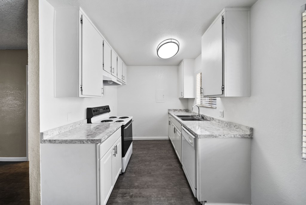 A kitchen with white cabinets and a marble countertop.