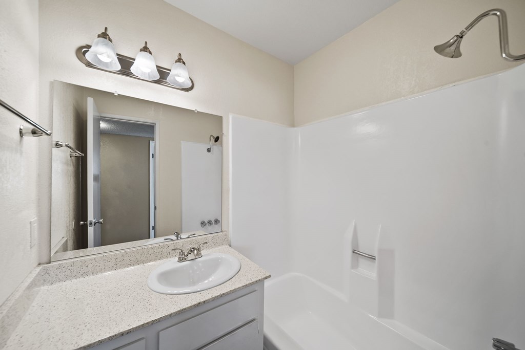 A white sink is in a bathroom with a white tub and a mirror.