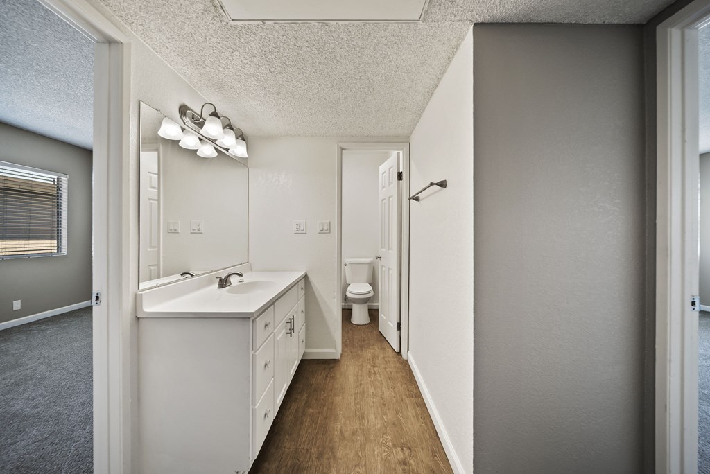 A bathroom with a toilet, sink, and mirror.