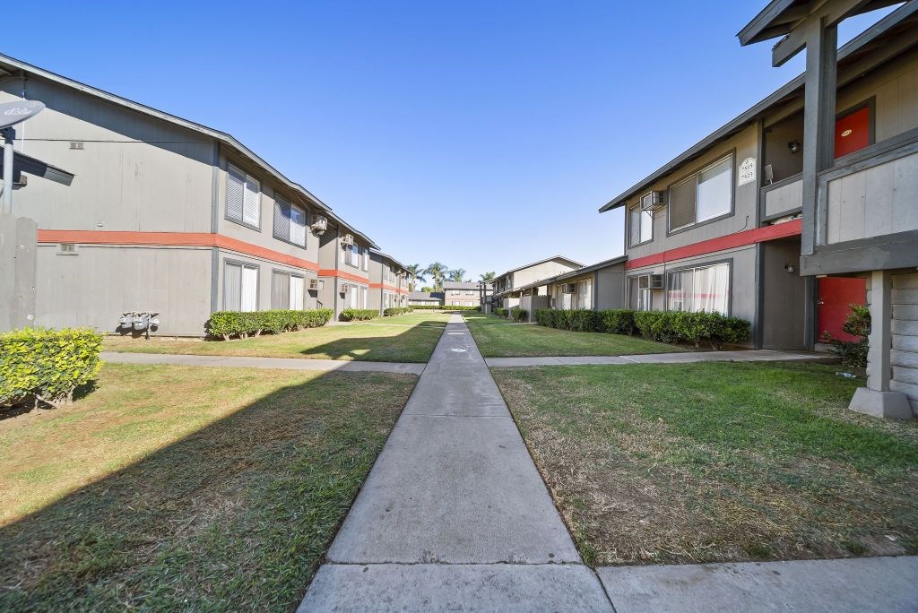 A long concrete walkway separates two rows of identical houses.