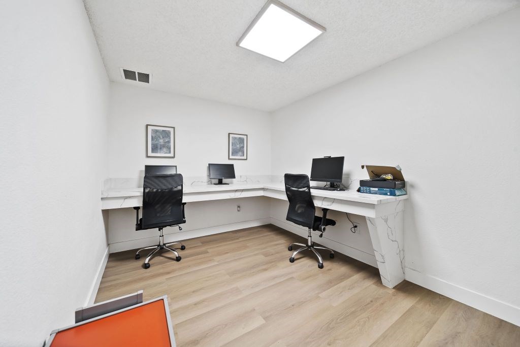 A white room with a desk and two chairs.