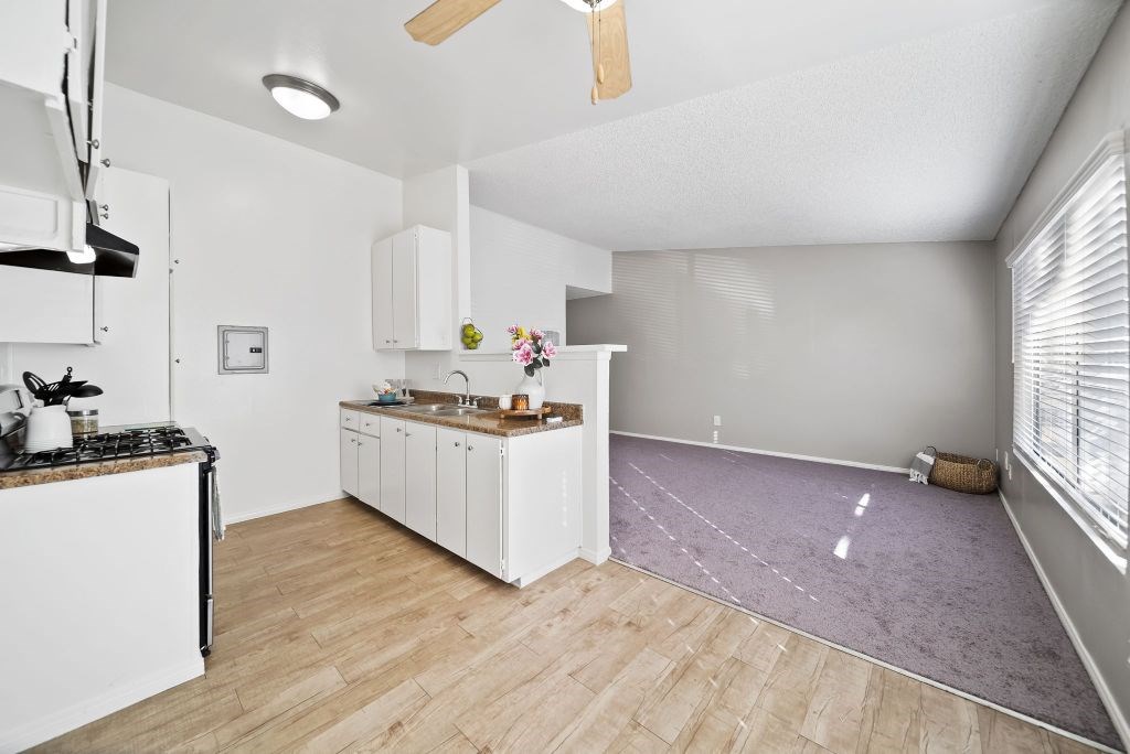 A kitchen with white cabinets and a wooden floor.
