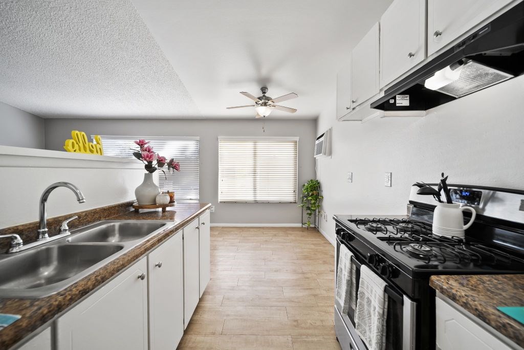 A kitchen with a black stove top oven and a black counter top.