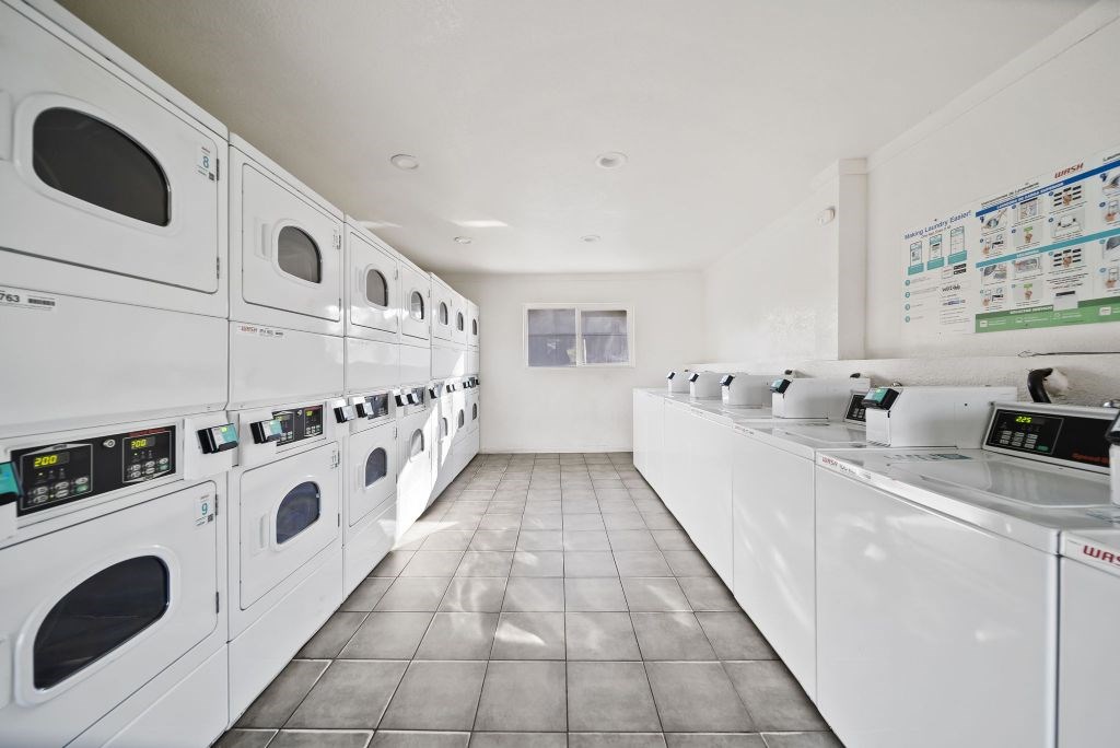 A row of white front loading washing machines in a laundromat.