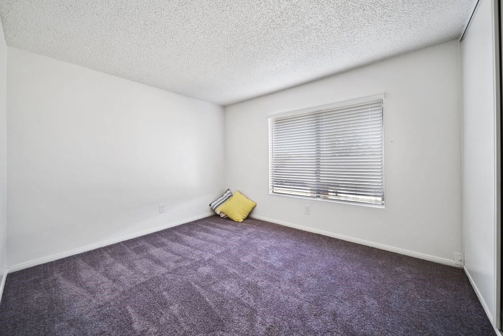 A room with a window and a yellow bag on the floor.