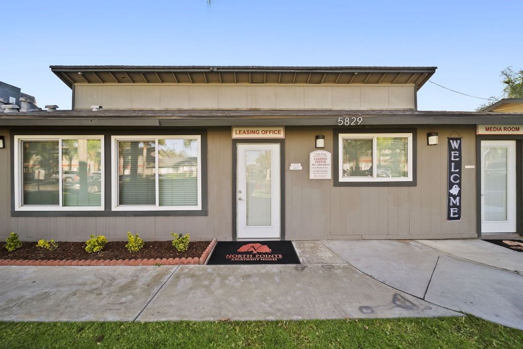 The front of a building with a leasing office and media room.