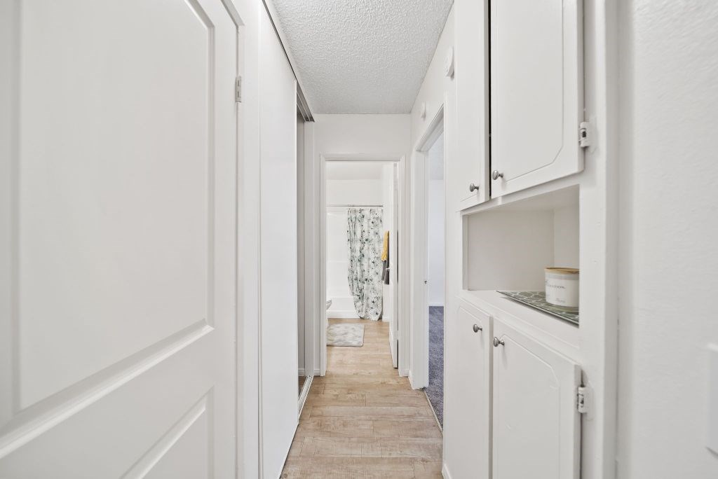 A long hallway with white doors and cabinets.