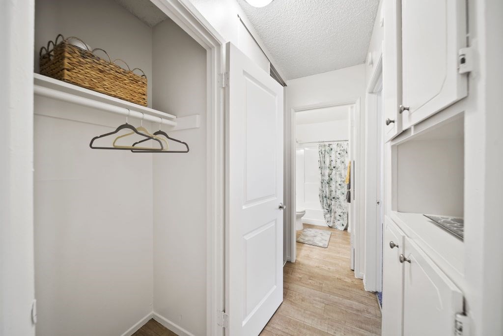 A hallway with a white door and a basket on the shelf.