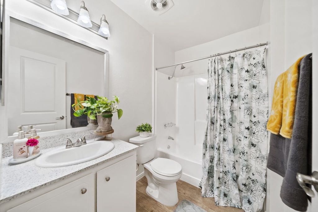 A white bathroom with a floral shower curtain.