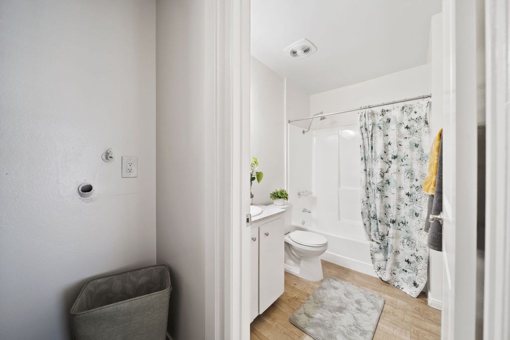 A white bathroom with a toilet, sink, and shower.