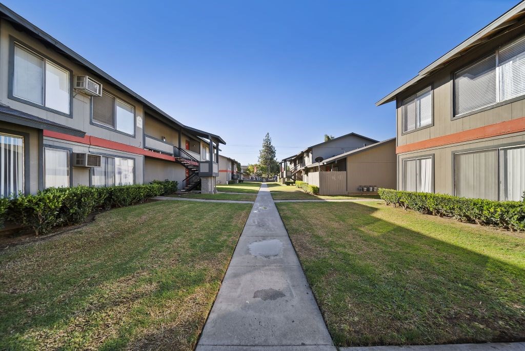 A long concrete walkway separates two rows of houses.