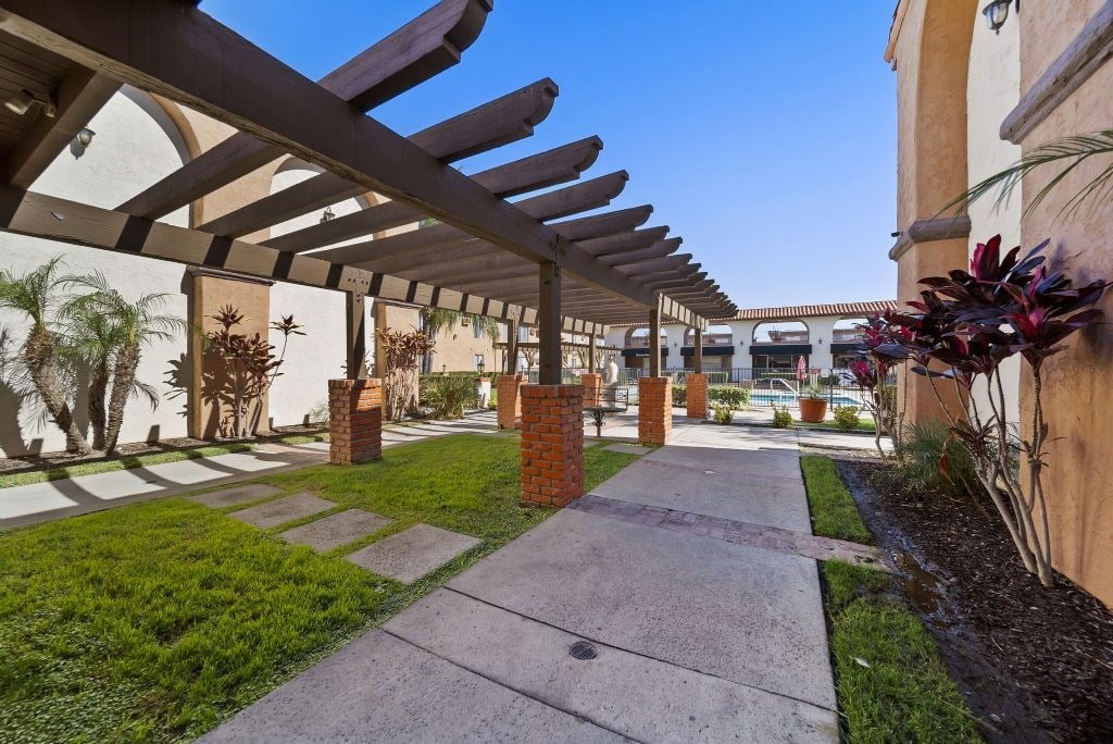 A walkway with a roof of wooden beams and brick pillars.