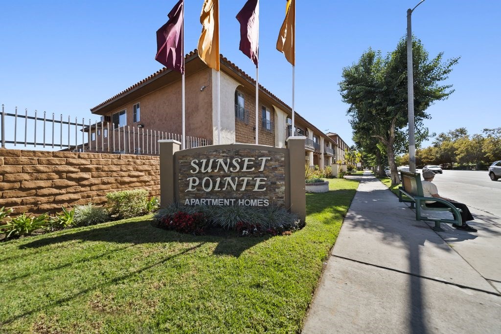 Sunset Pointe Apartment Homes sign with flags in front.