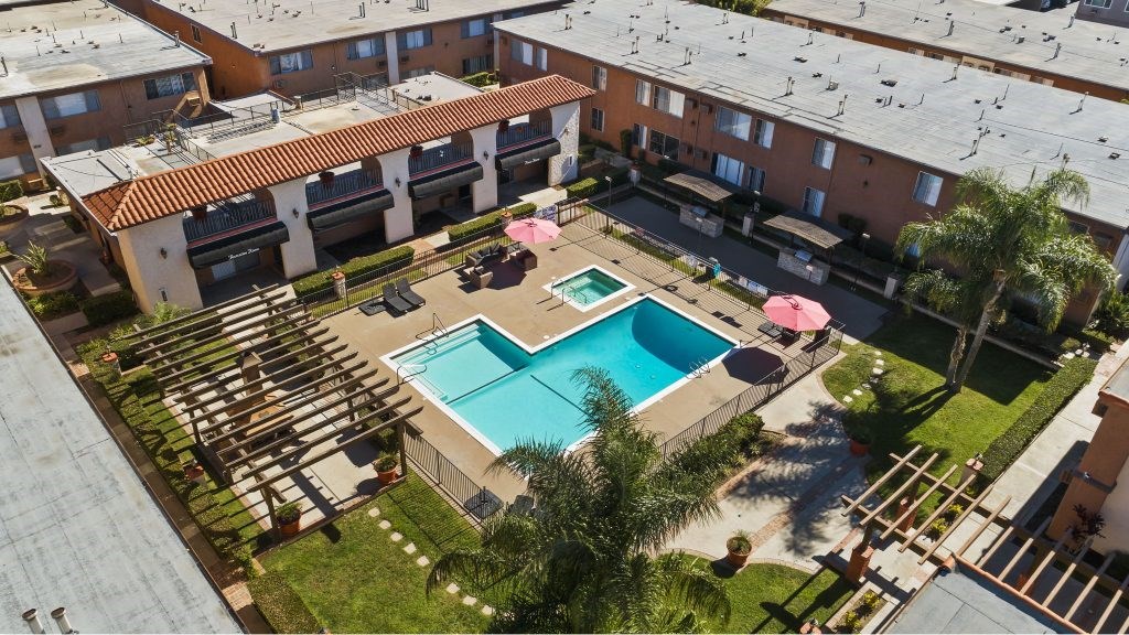 A swimming pool surrounded by a patio with chairs and umbrellas.