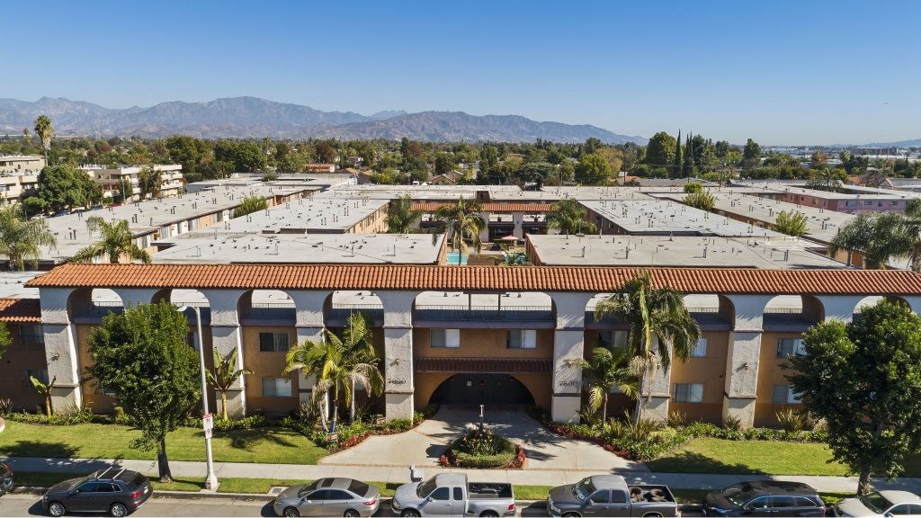 A large building with a red tile roof and a parking lot in front.