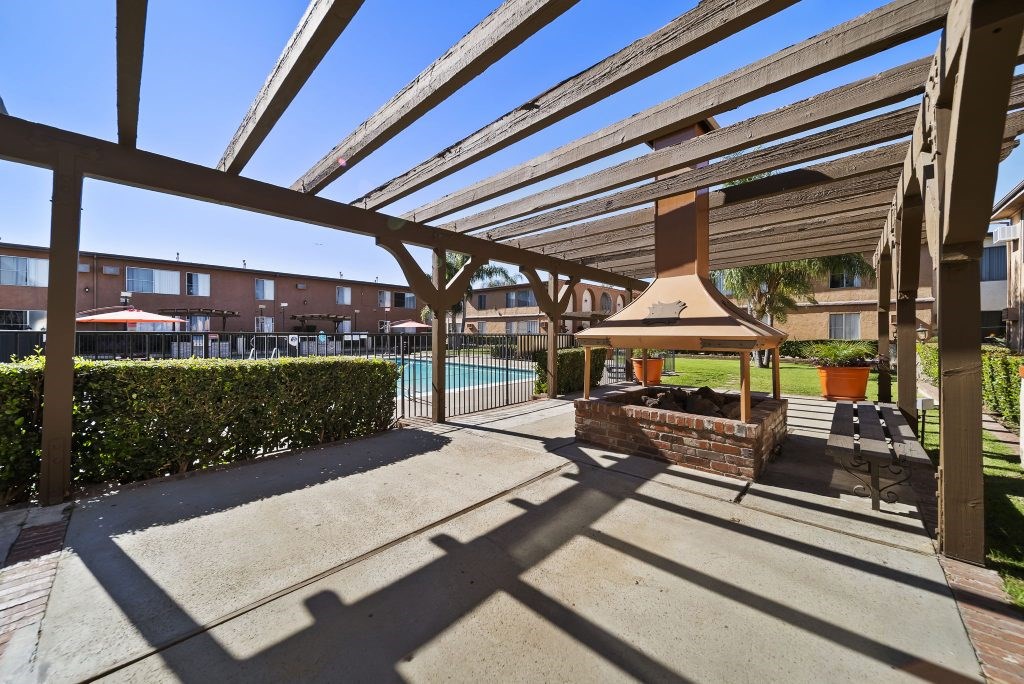 A patio with a table and chairs under a wooden pergola.