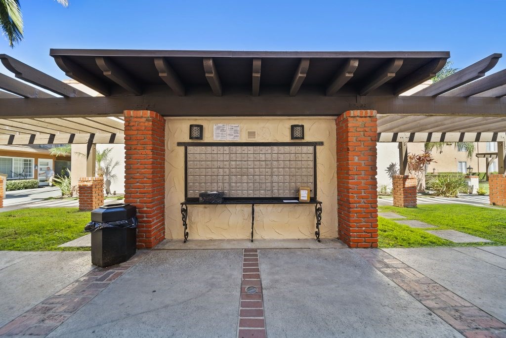 A small building with a black door and a black trash can in front of it.