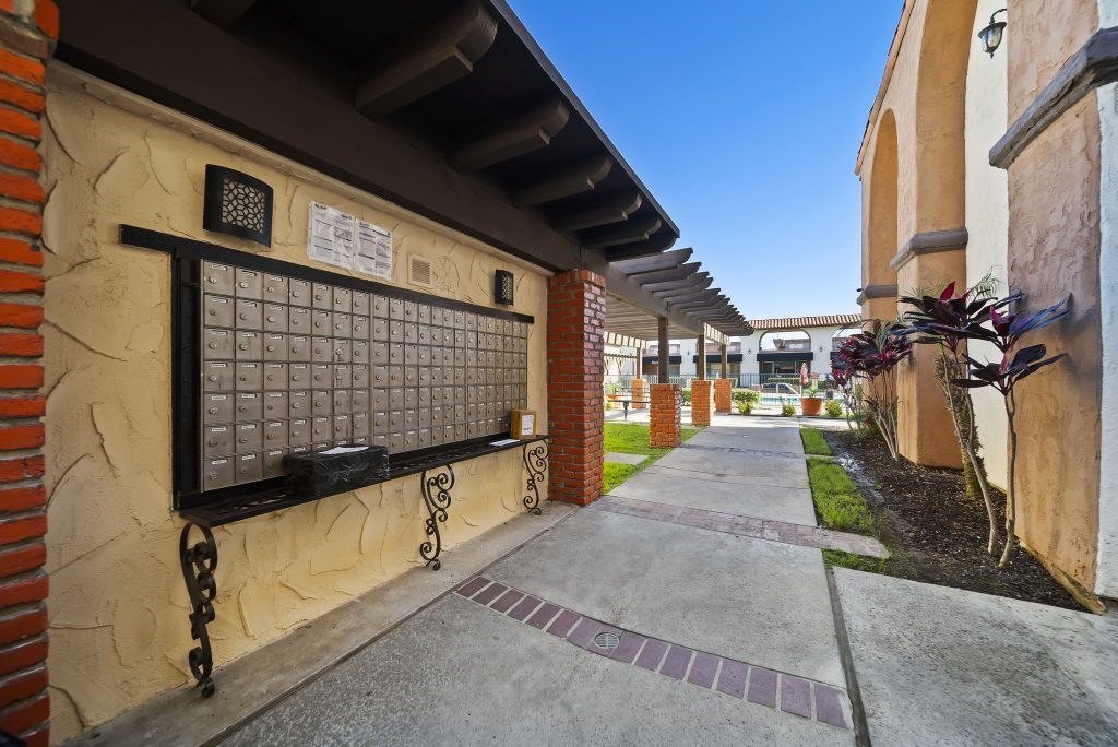 A long, narrow walkway with a brick wall and a metal gate.