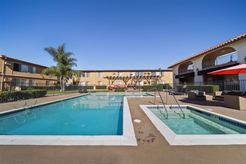 A large outdoor swimming pool with a slide and a smaller pool with a fountain.