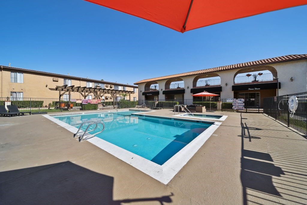 A large swimming pool with a red umbrella above it.