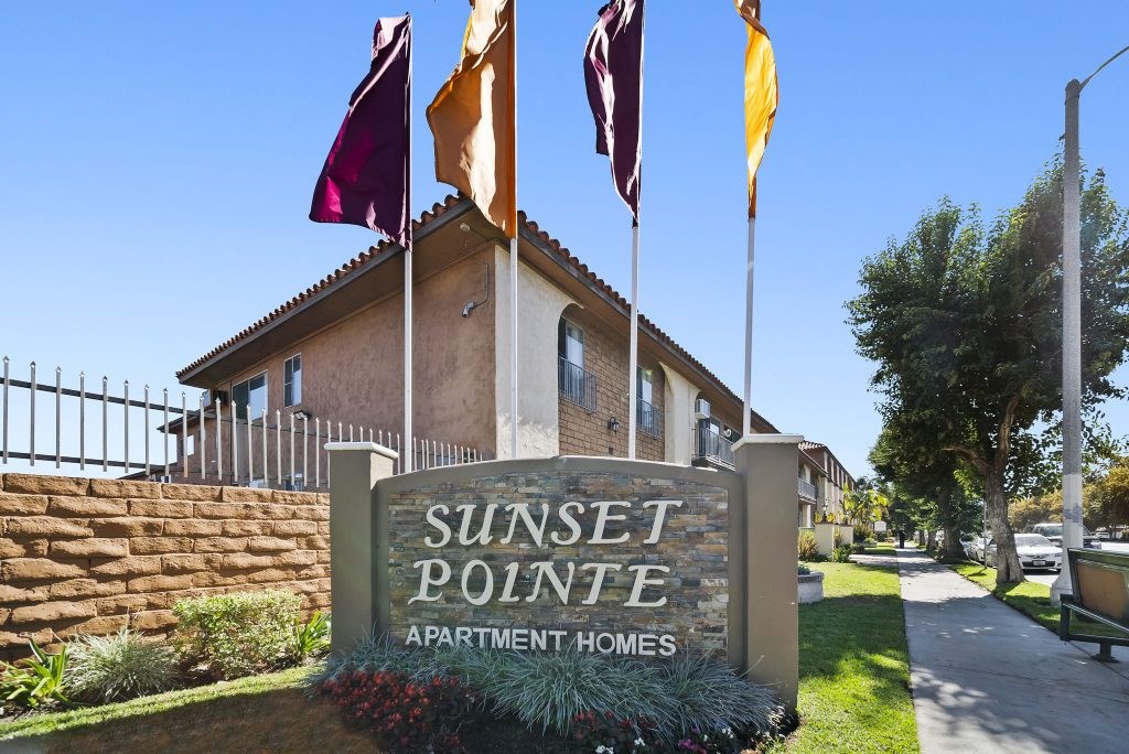 Sunset Pointe Apartment Homes sign with flags in front.