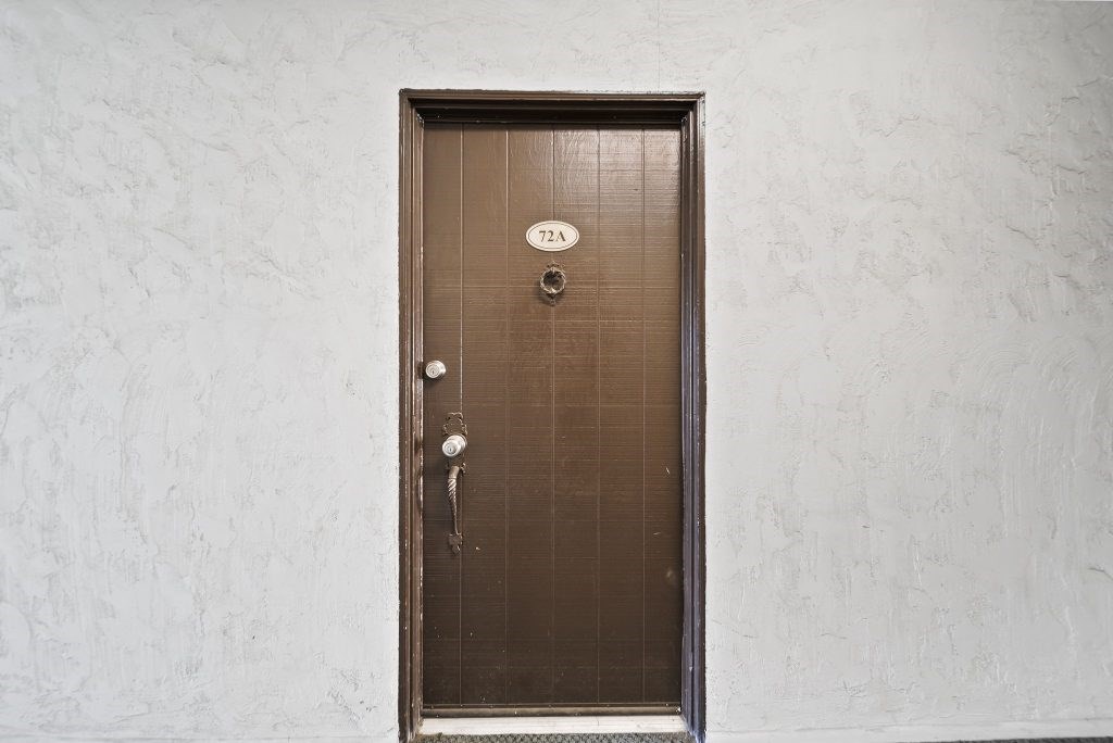 A brown door with a silver handle and a number 122 on the top left.