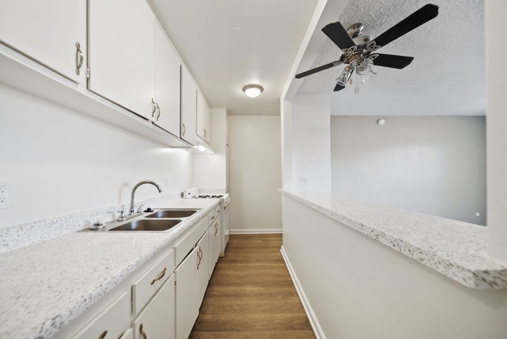 A kitchen with white cabinets and a marble countertop.