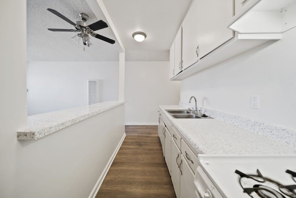 A kitchen with white cabinets and a white counter top.