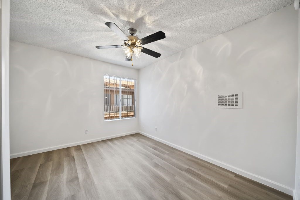 A room with a ceiling fan and a window with bars.