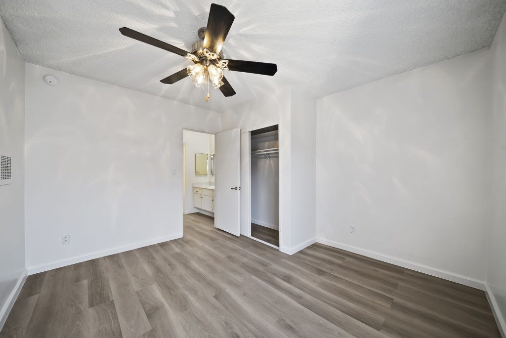 A room with a ceiling fan and wooden flooring.