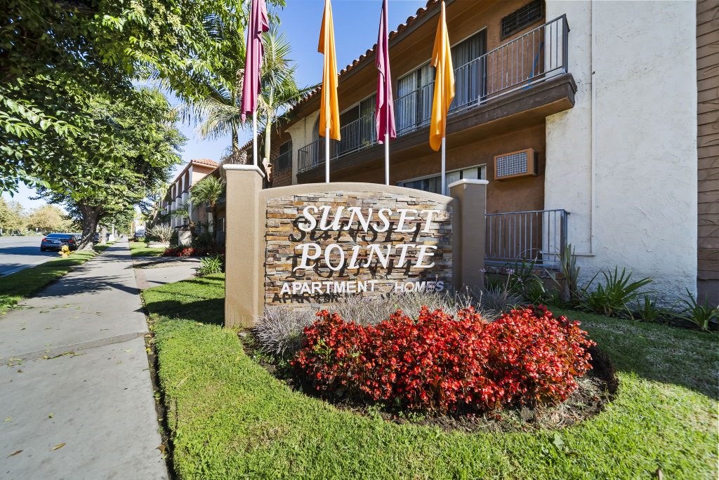 Sunset Pointe Apartment Homes sign with red flowers in the foreground.