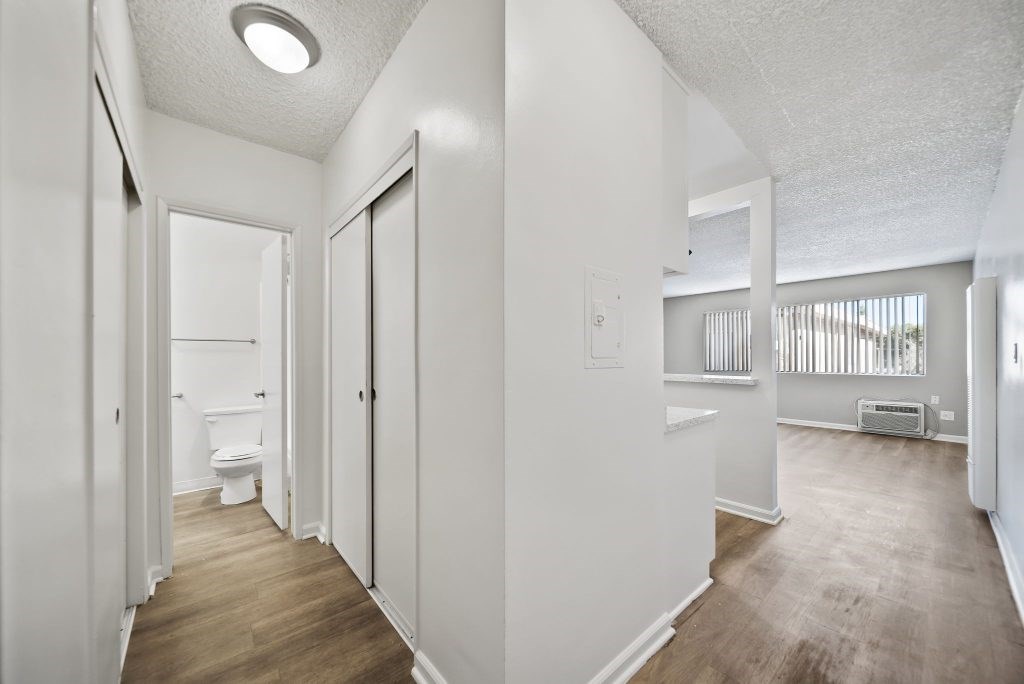 A white bathroom with wood flooring and a window.