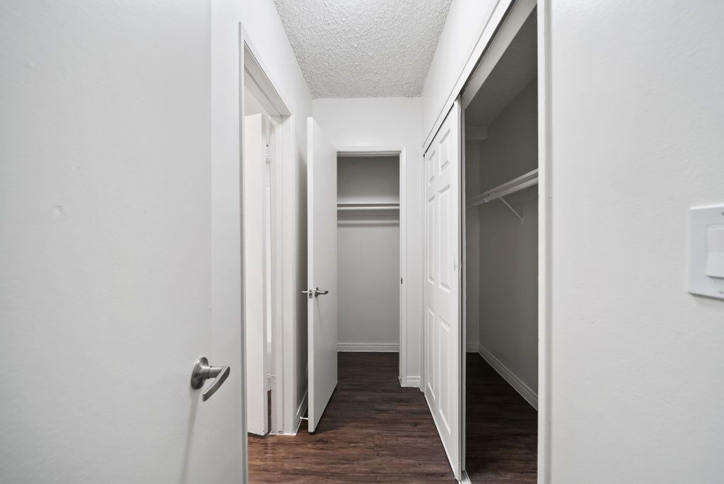 A white hallway with a door on the left and an open door on the right.