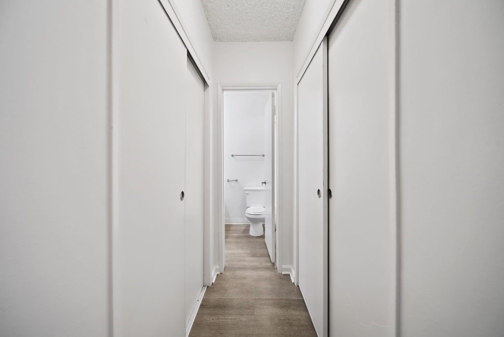 A long hallway with a toilet at the end.