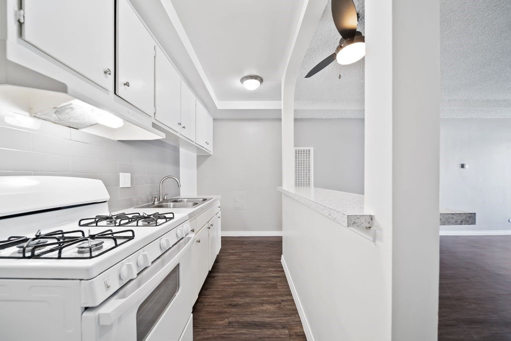 A white kitchen with a stove and a fan.