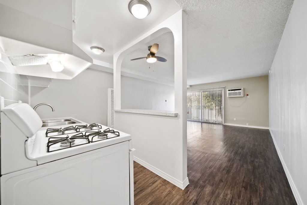 A white kitchen with a stove and a fan.
