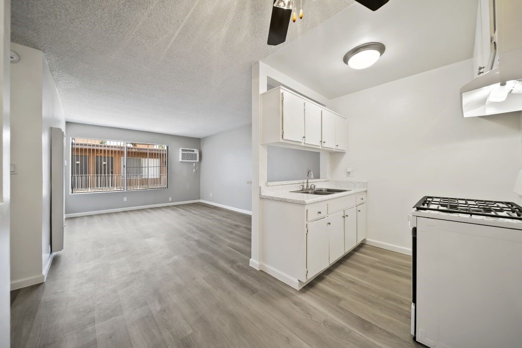 A kitchen area with a stove, sink, and cabinets.