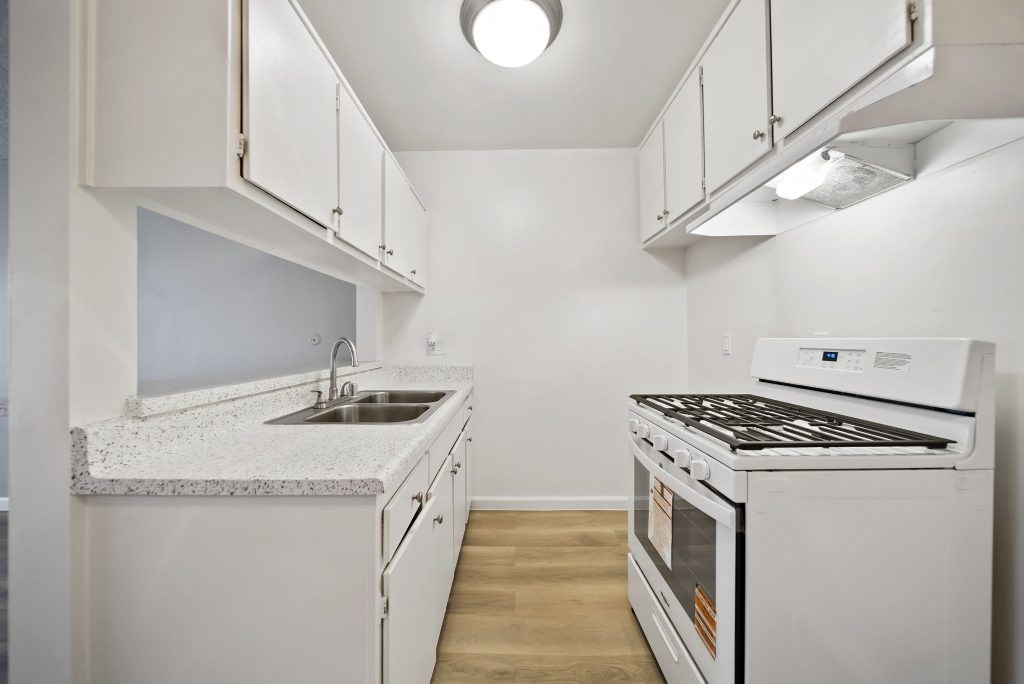 A white kitchen with a stove and sink.